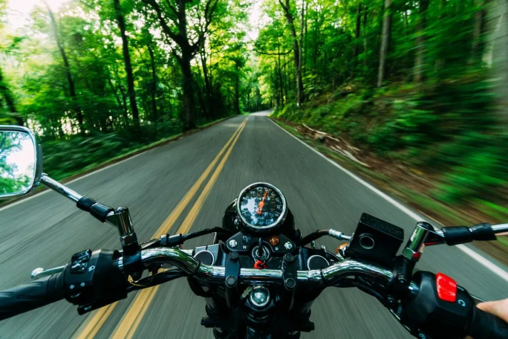 Rider view over the handlebars of a motorcycle on a forest road